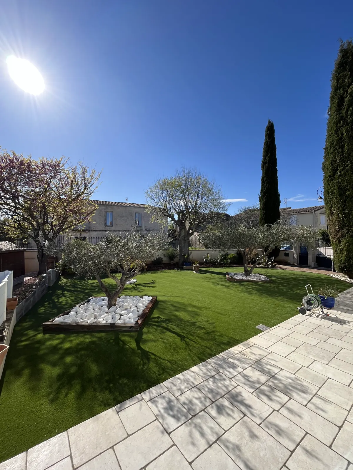 Jardin avec dallage clair, gazon, massifs minéraux et cyprès de Provence