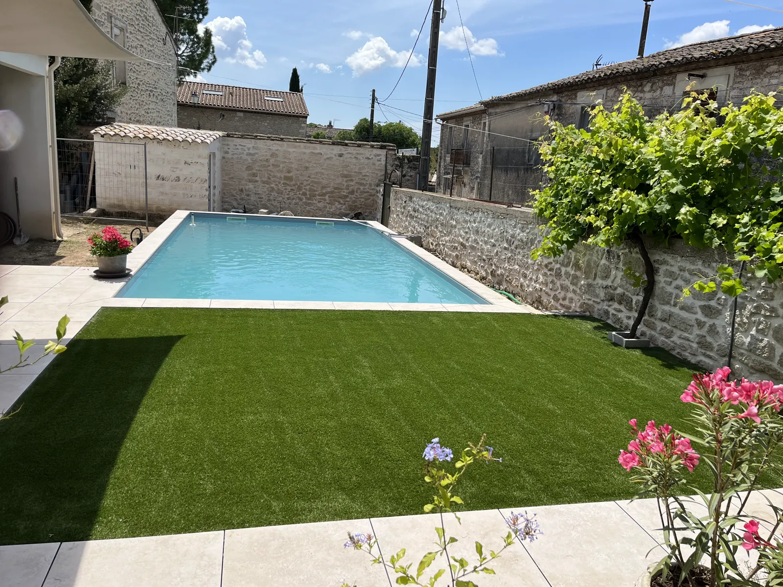 Jardin méditerranéen avec gazon, laurier-rose et piscine entourée de dallage