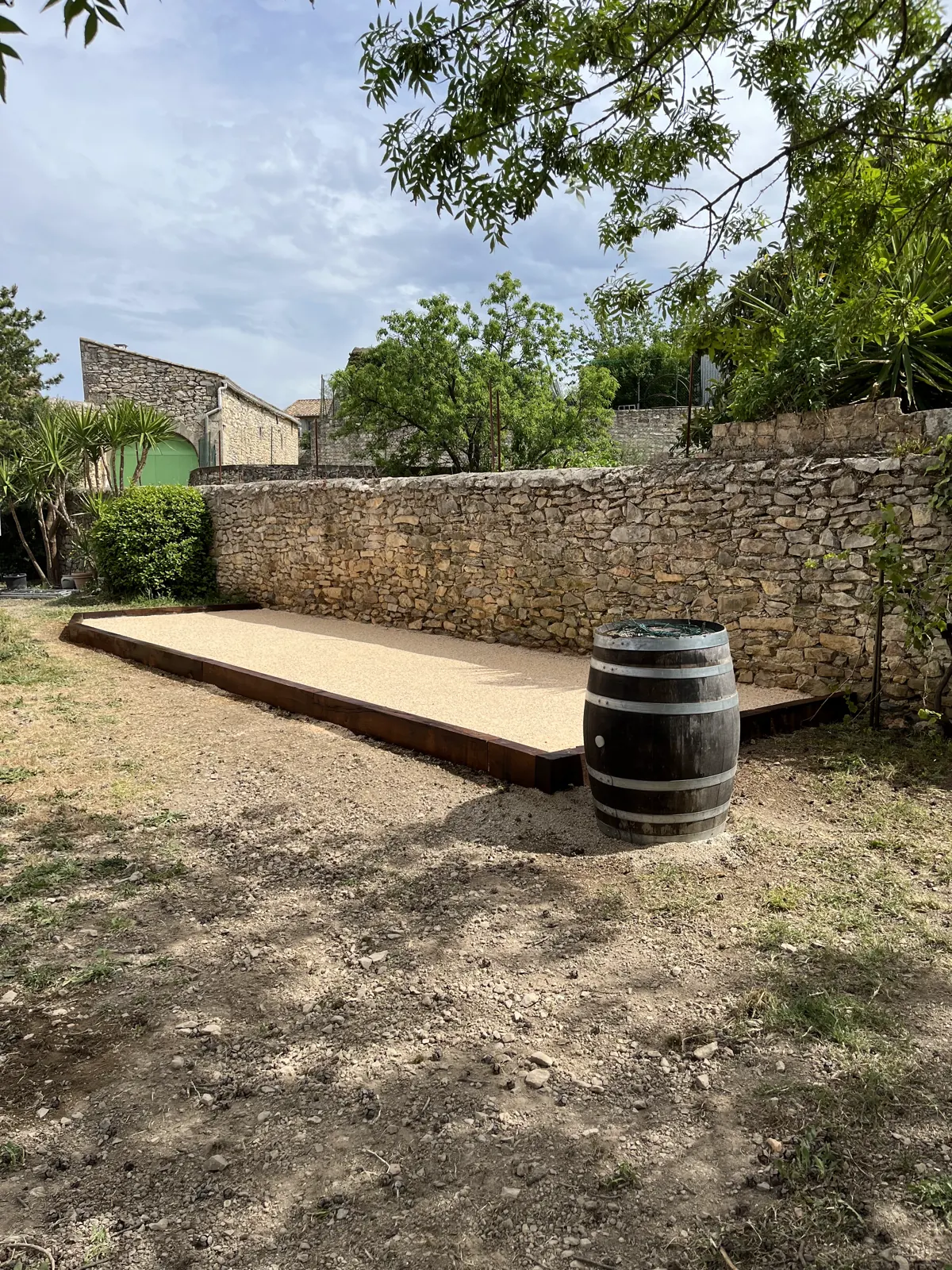 Terrasse en bois en cours de réalisation devant un mur en pierre sèche